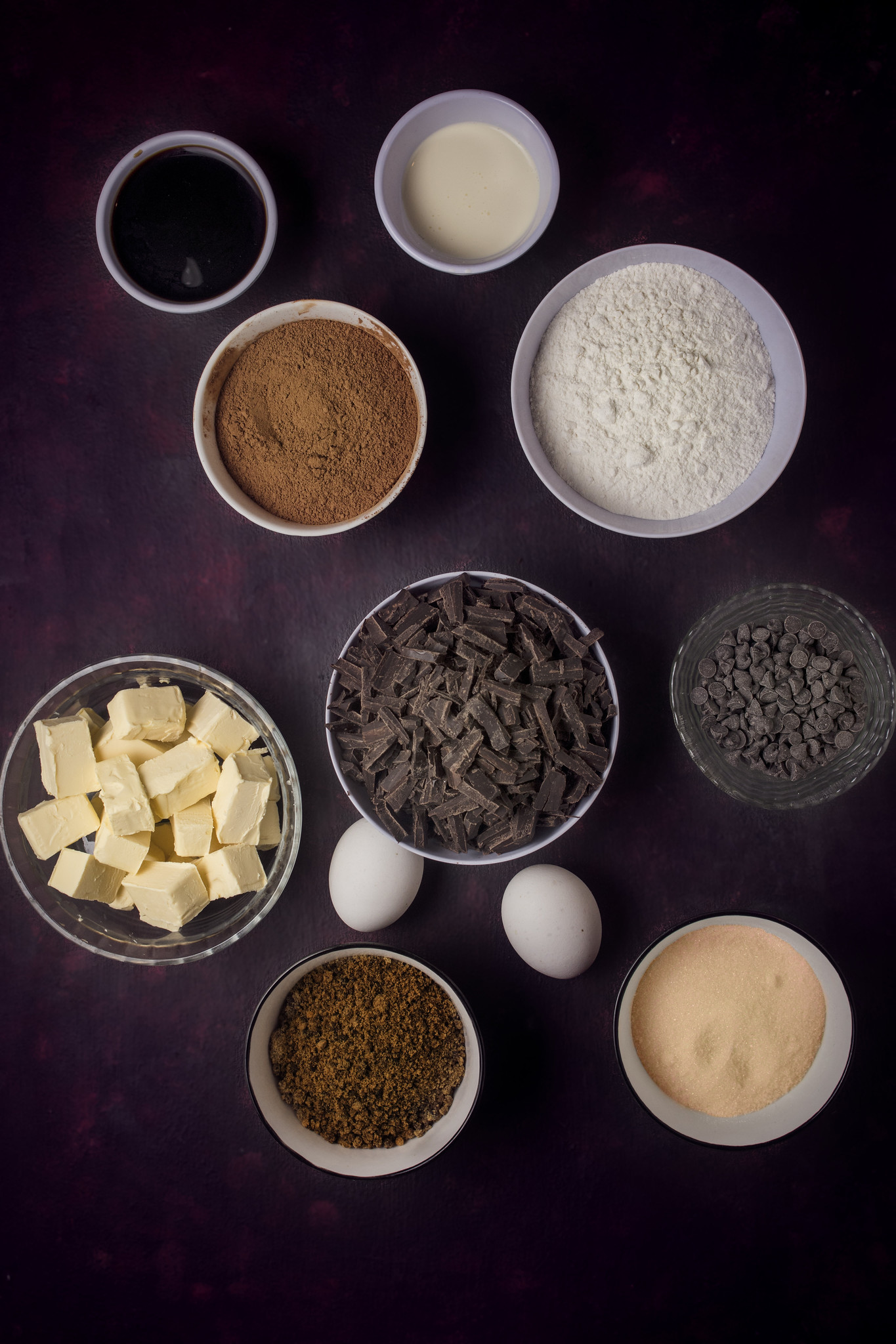 Ingredients for Chocolate Ghoulyard Cake arranged in bowls on a dark background.